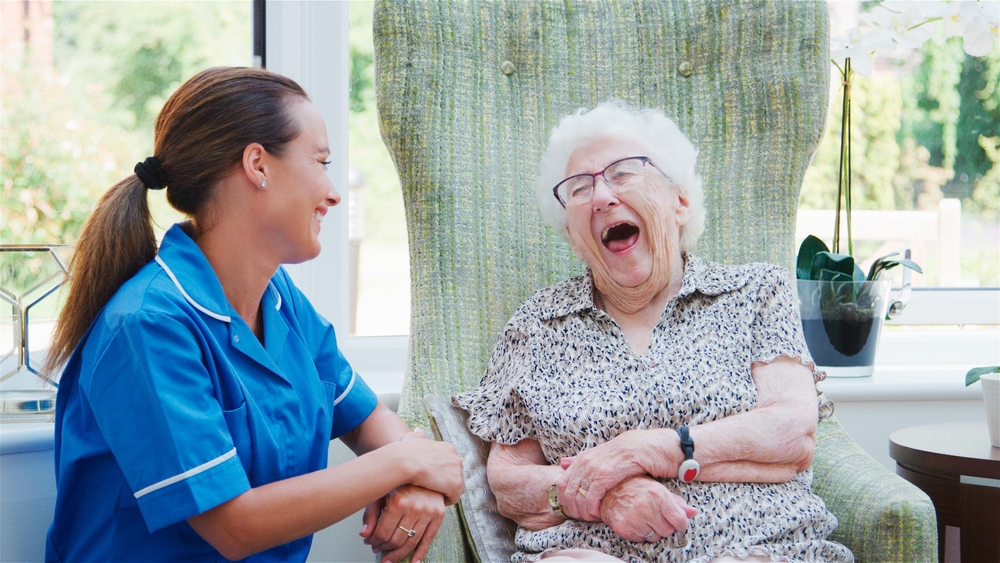 Laughing,Senior,Woman,Sitting,In,Chair,In,Residents,Lounge,And